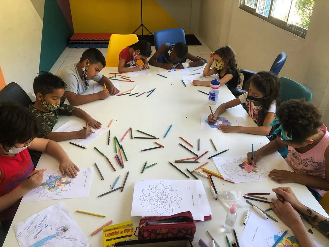 Crianças desenhando mandalas com lápis de cor em oficina