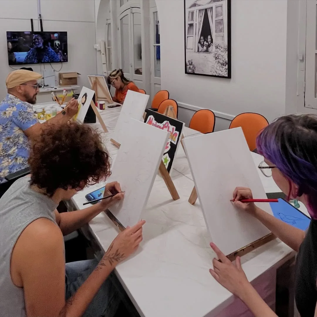Adultos pintando em cavaletes durante oficina de pintura